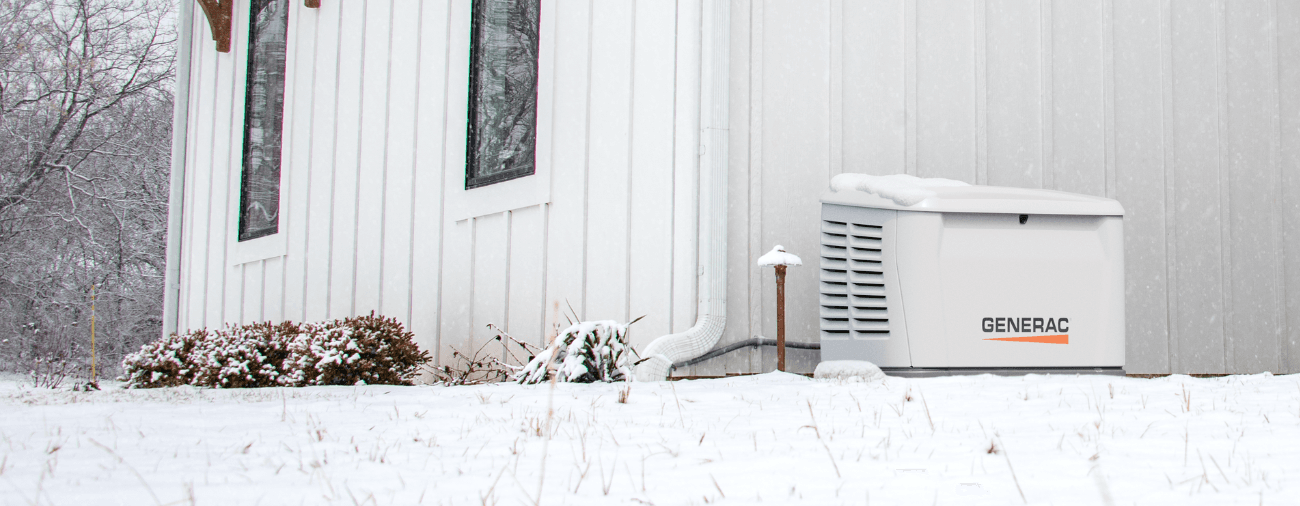 Generac home standby generator installed beside a house in the snow
