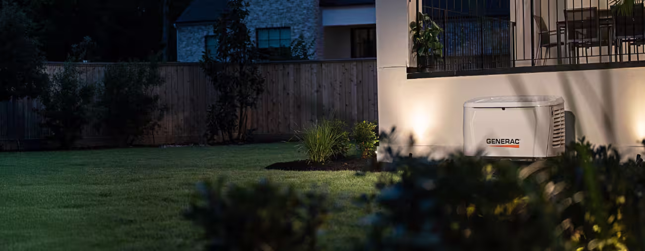 Generac home standby generator installed and running beside a house at night